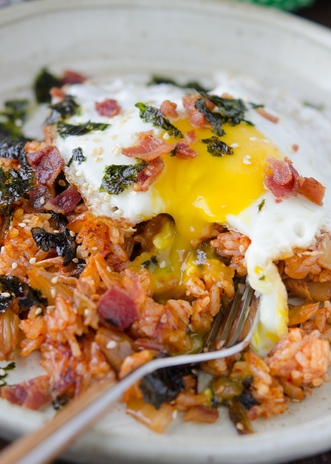 Creamy egg yolk is running over kimchi fried rice with bacon.