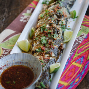 Grilled Fish is served with Soy Lime Chili Sauce and lime wedges.