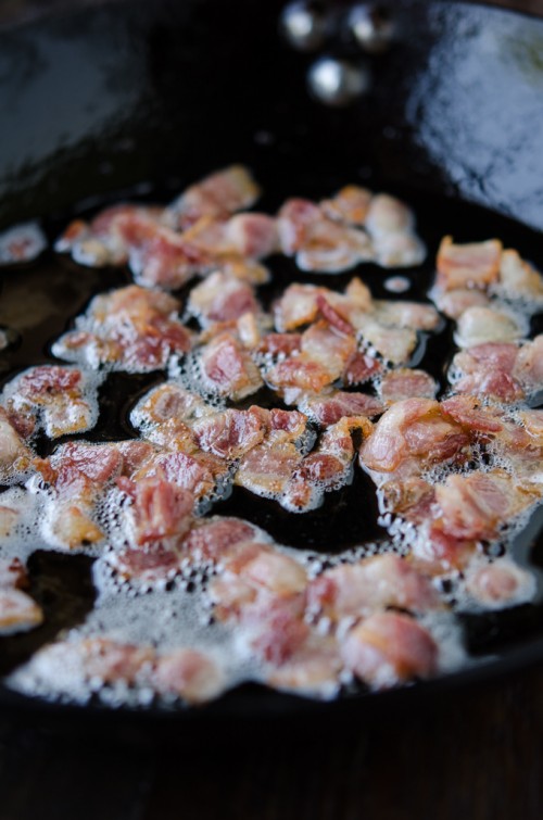 Bacon pieces fried to crisp texture in a skillet.