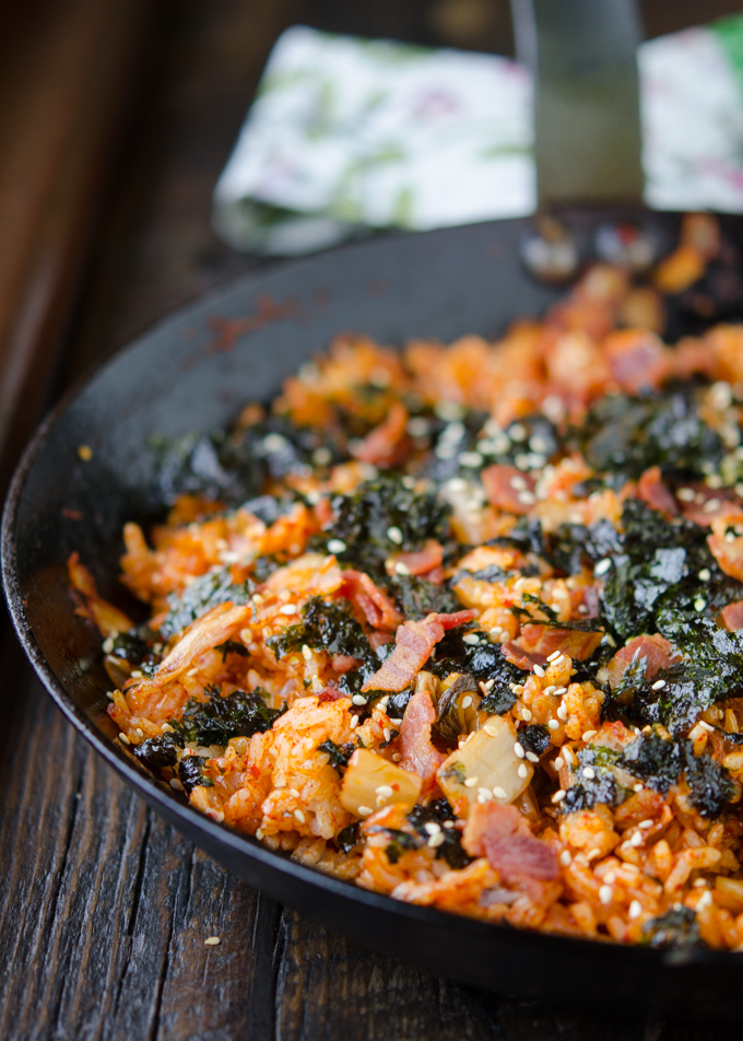Kimchi Fried Rice garnished with crisp bacon pieces, crumbled seaweed and sesame seeds.