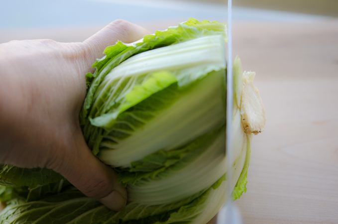 A knife is cutting off the tip of Korean bomdong cabbage