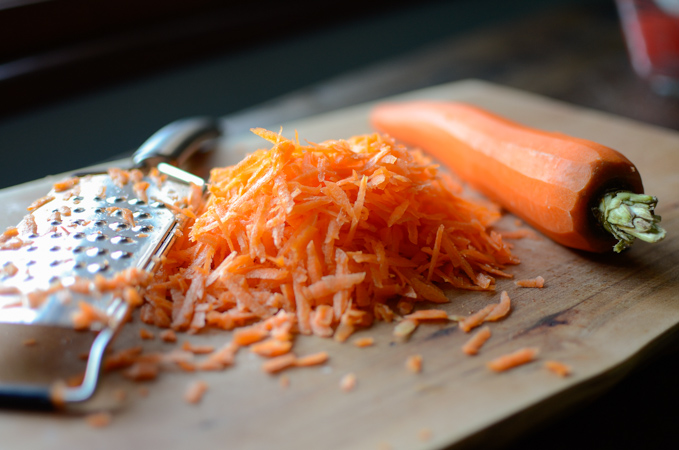 A fresh carrot is grated to make carrot bread.