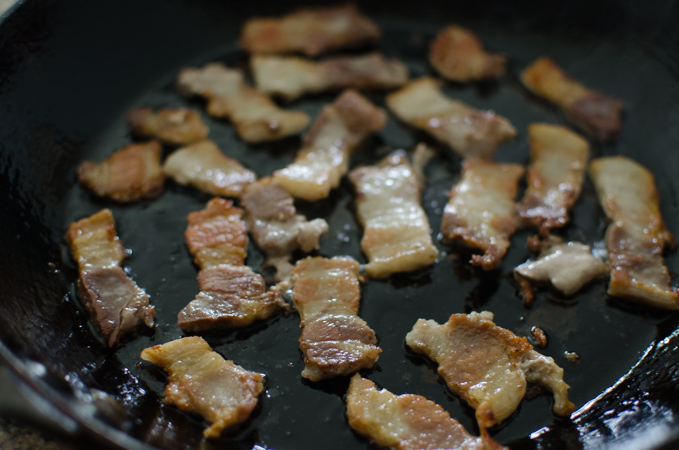 Pork belly fried in a skillet.