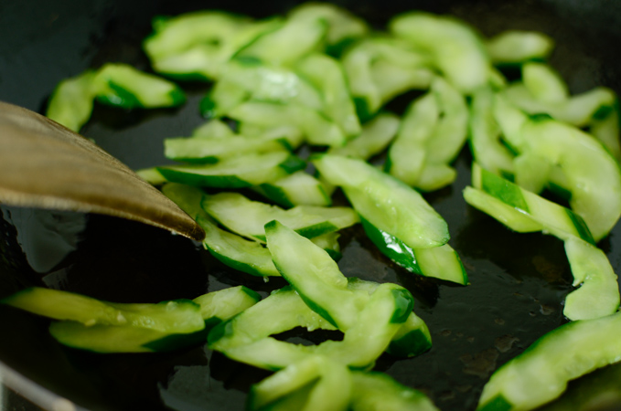 cucumber slices are being stir-fried to make beef cucumber stir-fry.