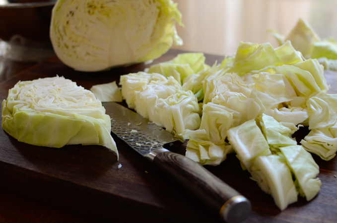Green cabbage is cut up with a knife to make kimchi.