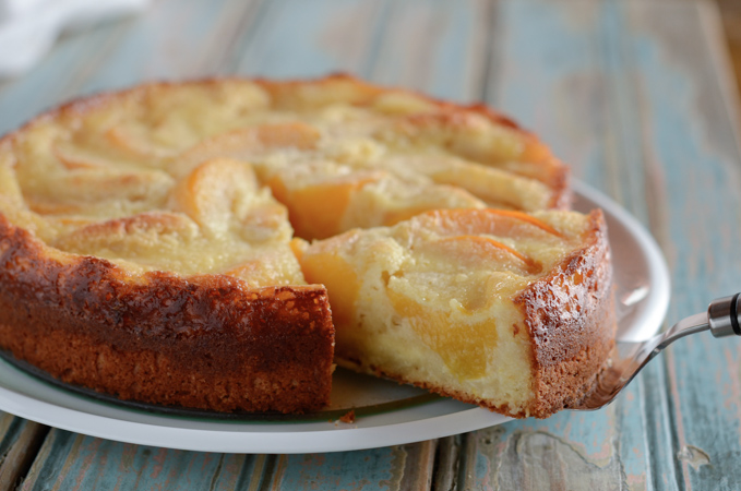 A slice of moist German peach cake is cut out from a plate