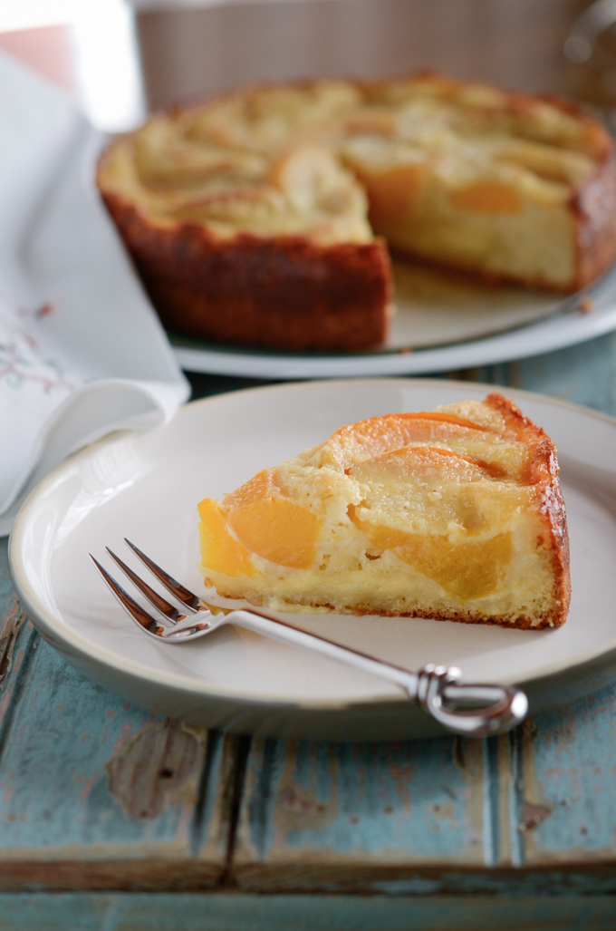 A slice of peach Kuchen shows creamy vanilla custard in the layer.