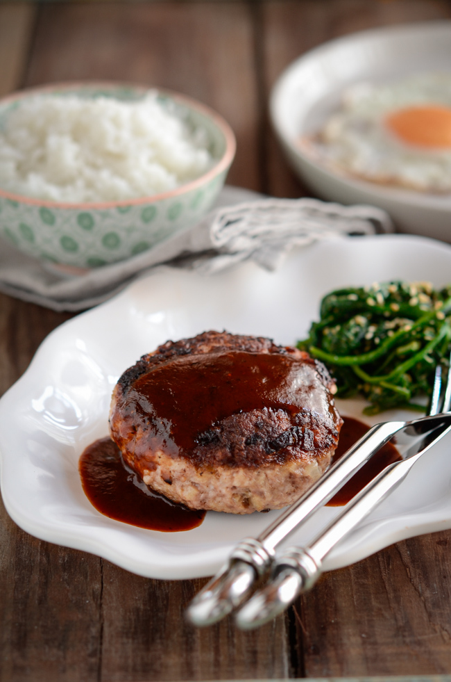 Japanese hamburger steak is drizzled with red wine sauce and served with rice and spinach.