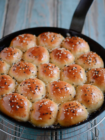 Honeycomb patterned beehive sweet buns are soaked in honey syrup in a skillet.