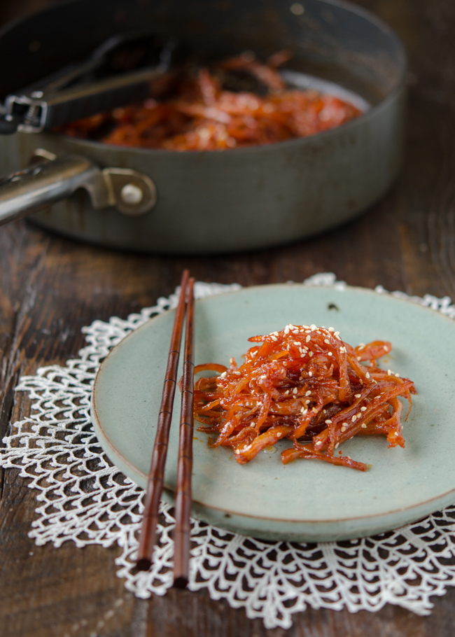 Korean squid side dish is served on a green plate with chopsticks.