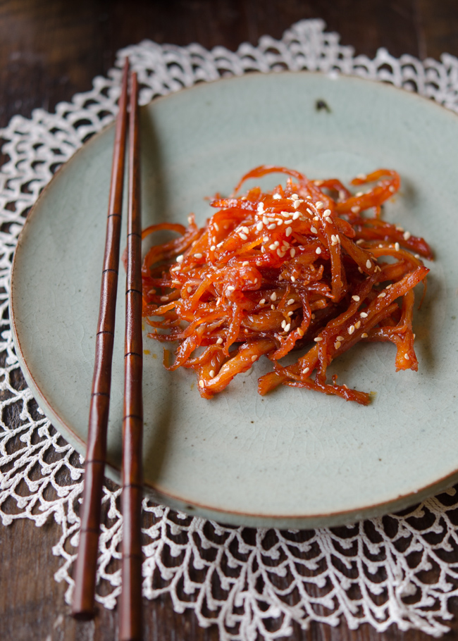 Korean shredded squid side dish is on a greet plate with a pair of chopsticks.