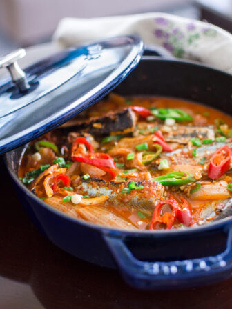 Kimchi Jjigae is made with canned mackerel pike fish in a blue pot.