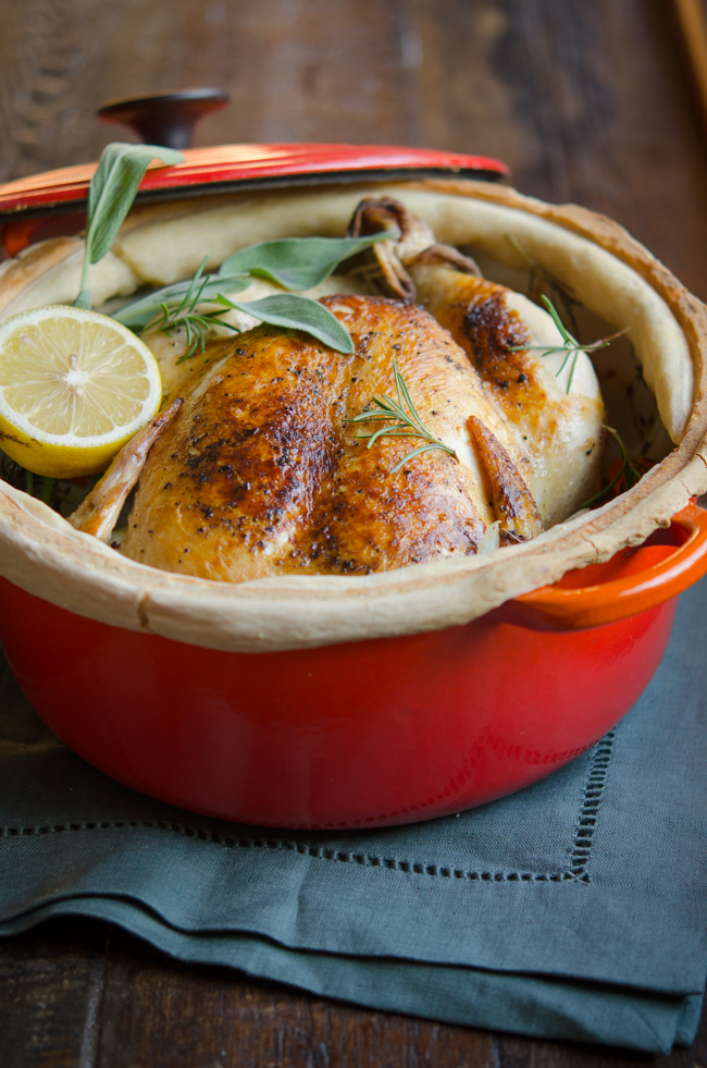 A whole chicken is pot roasted in a sealed dutch oven with lemon and herb.