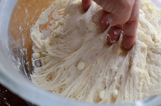 White chocolate chip bread is risen well showing the spider web-like look in the dough when pulled.