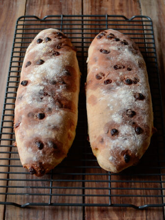 Two loaves of club med white chocolate bread are cooling on a wired rack.