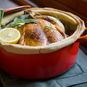 A whole chicken is pot roasted in a sealed dutch oven with lemon and herb.