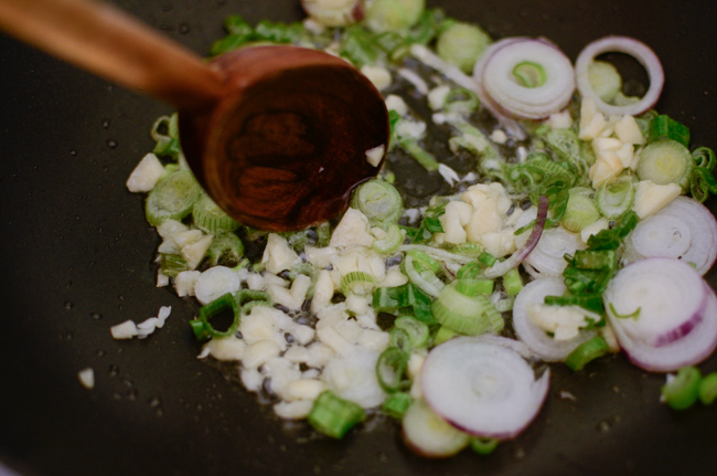 Green onion and garlic is sautéing in a wok.