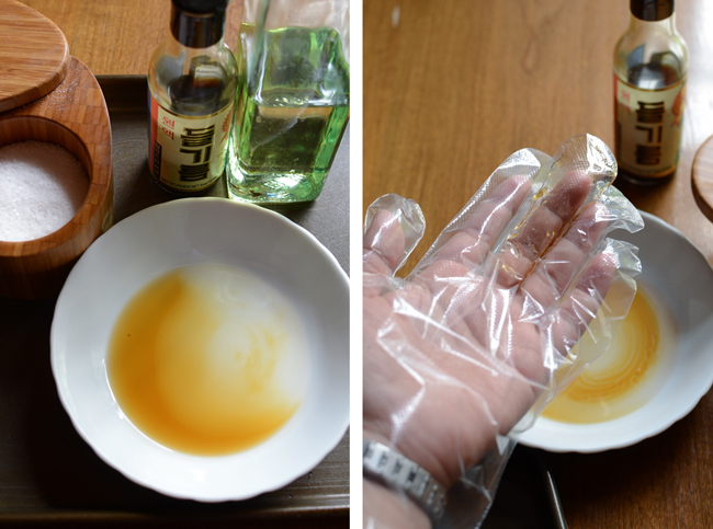 A hand with a disposable plastic glove is rubbing the oil mix.