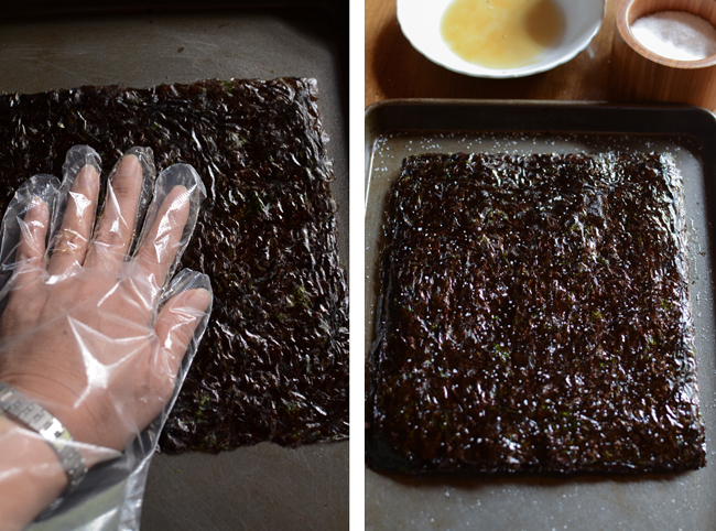 A hand with plastic glove is rubbing the oil to the seaweed sheets