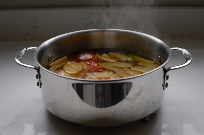 A pot of vegetable and fruit stock is cooling on the counter.