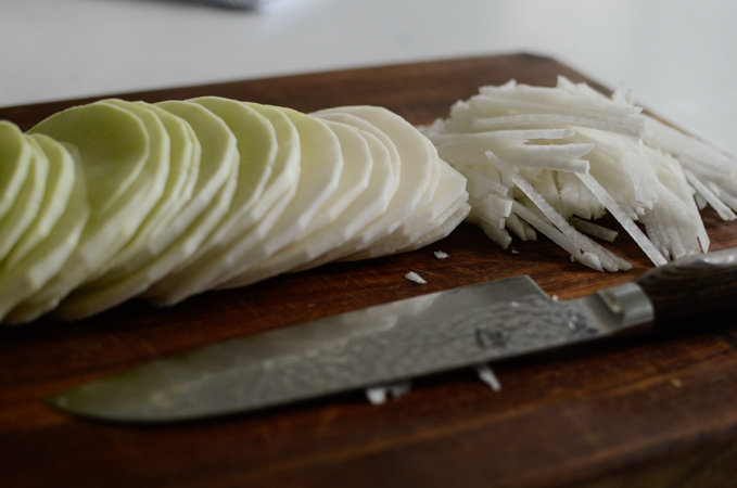 Thin round slices of radish is cut into thin matchstick strips.