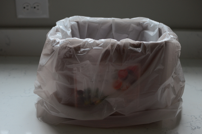 A white plastic bag is used to line inside a kimchi container.