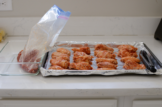 Marinated chicken wings are placed on a baking pan lined with foil.