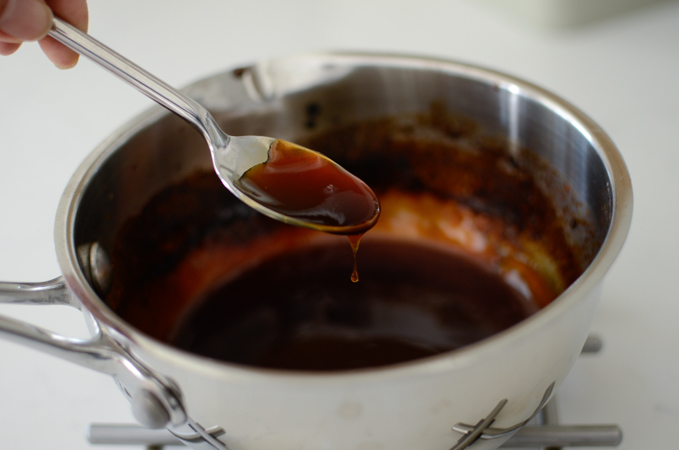 A spoon is showing thickened teriyaki sauce consistency by drizzling over the sauce.
