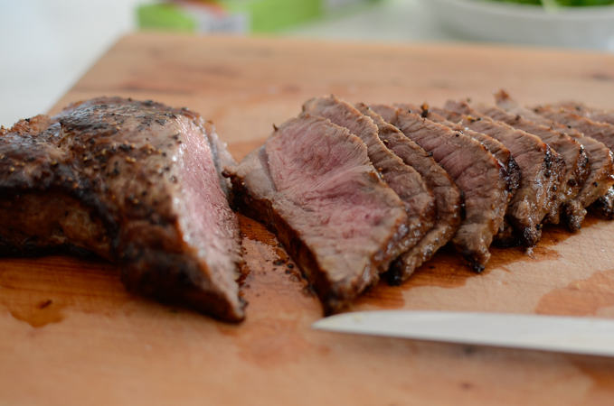 Seared steak is sliced and showing its medium doneness inside.