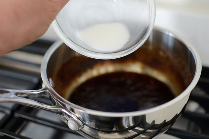 Cornstarch slush is adding to the sauce mixture in a small sauce pan on the stove.