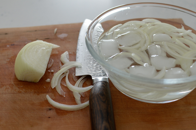 Onion is sliced and soaking in the bowl of cold water.
