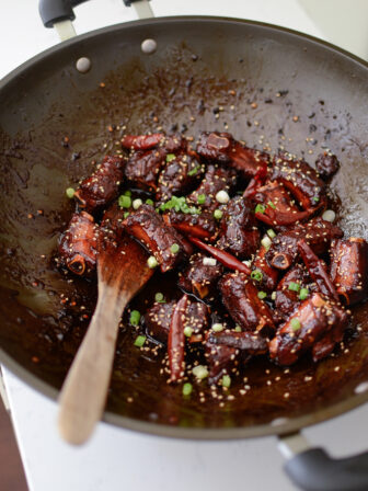 Chinese Sweet and Sour Pork Ribs are coated with sticky caramelized sauce and garnished with green onion.