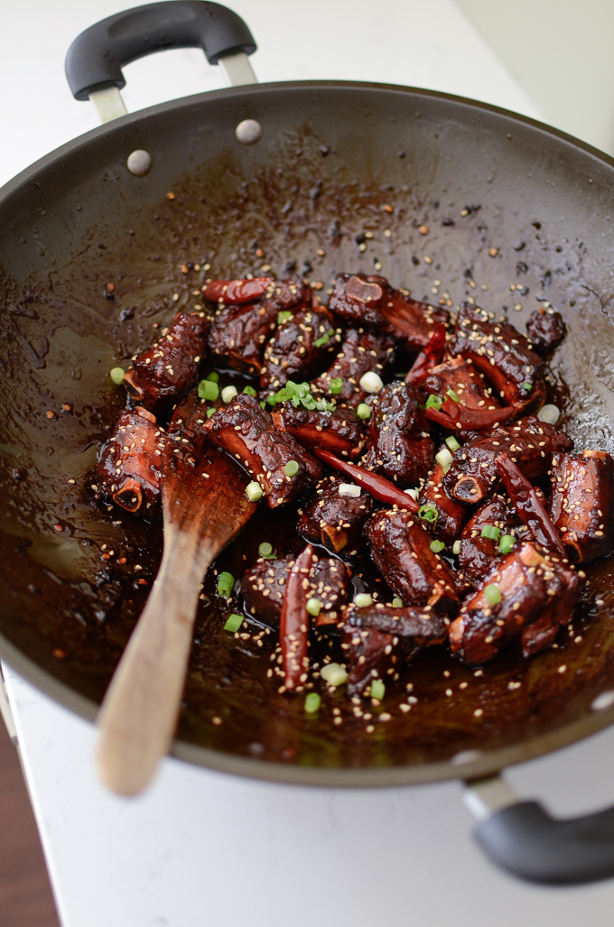 Chinese Sweet and Sour Pork Ribs are coated with sticky caramelized sauce and garnished with green onion.