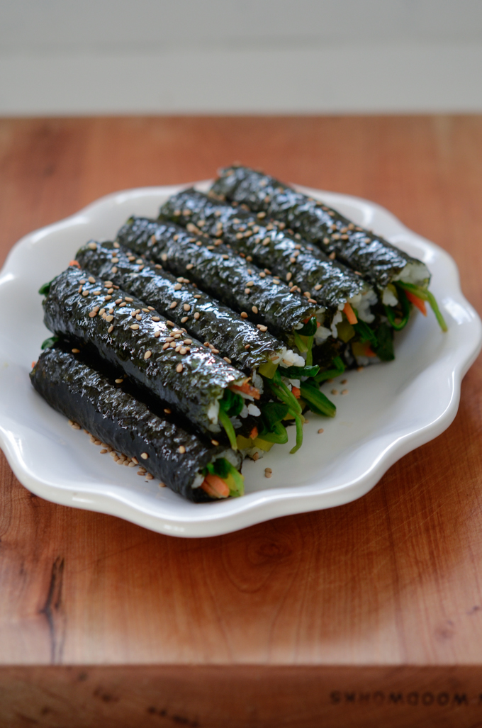 Mini Seaweed Rice Rolls (mayak gimbap/kimbap) are garnished with toasted sesame seeds.