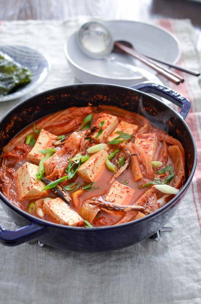 Kimchi jjigae made with dried anchovies and tofu is served in a blue pot.