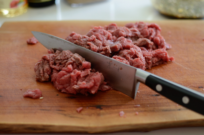Beef slices are gathered up and a knife is giving a few cuts.