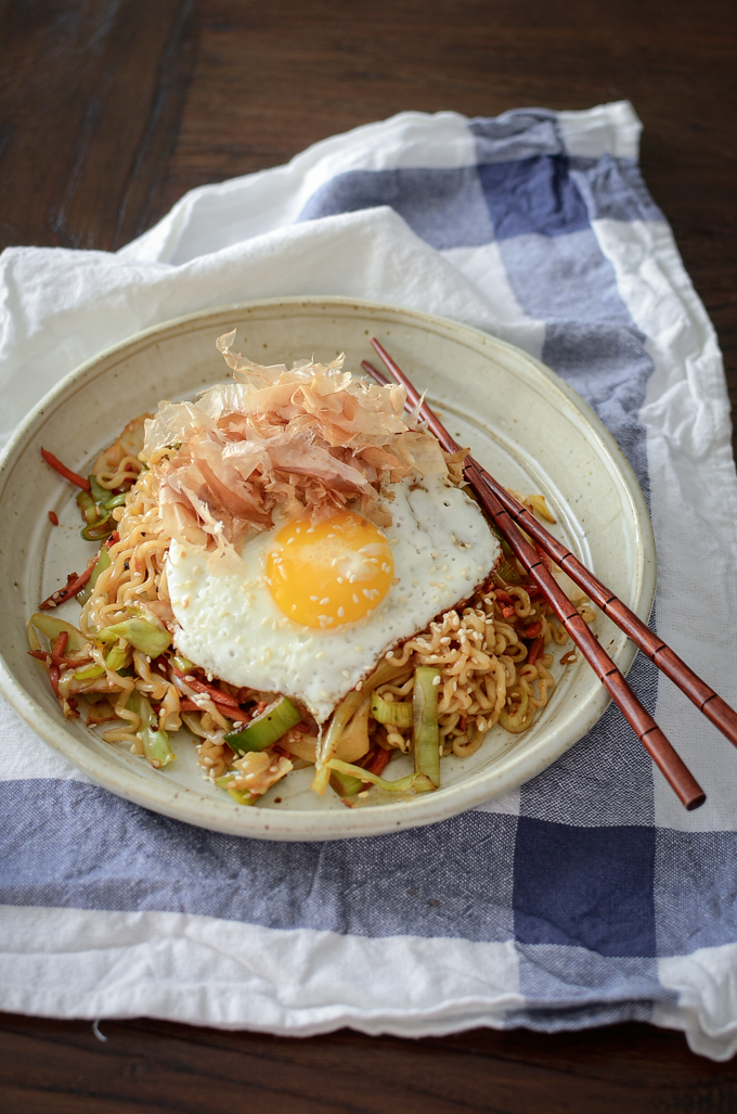 Quick ramen and vegetable stir-fry is topped with fried egg and bonito flakes in a bowl.