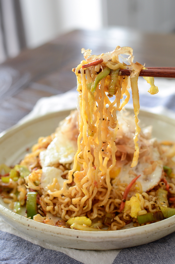 A chopstick full of stir-fried ramen and vegetables is ready to serve.