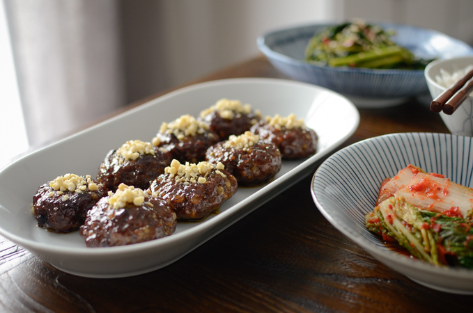 Korean beef patties are garnished with minced pine nuts on top in a white platter.
