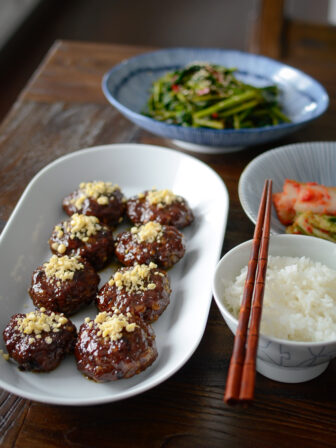 Honey glazed Korean beef patties are garnished with minced pine nuts are served with rice and kimchi on the side.