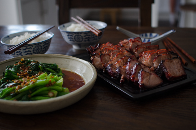 Choy sum dish is served with a plate of Char Siu and two bowls of rice.