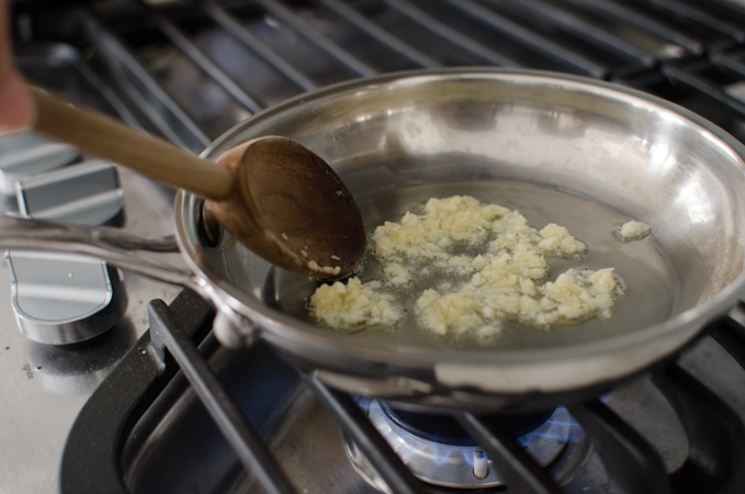 Minced garlic is cooking in oil in a small skillet over stove.