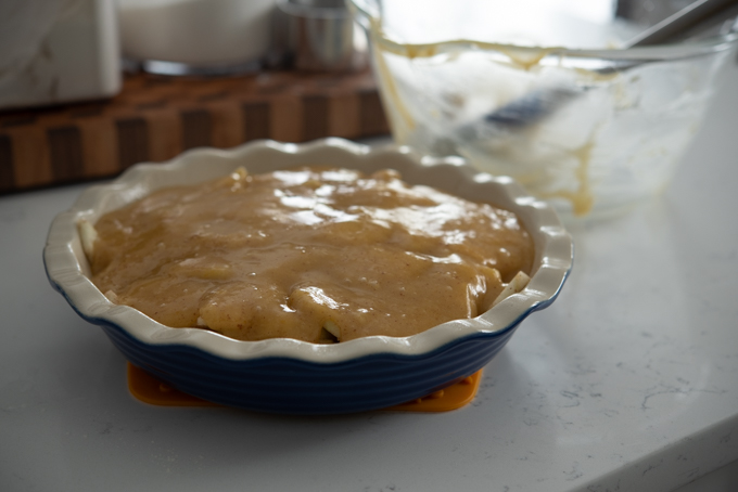 Browned butter and sugar batter covering the apple slices in a pie dish.