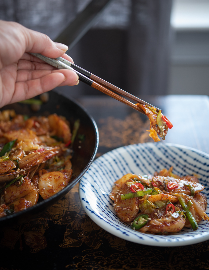 Chopsticks holding rice cake stir-fry with vegetables.