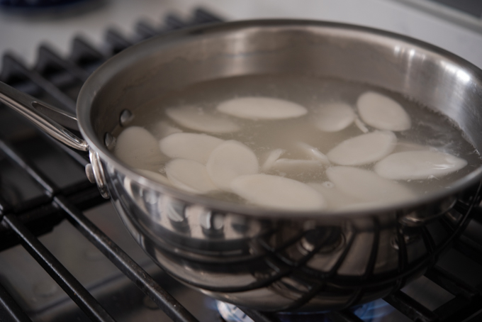 Rice cake rounds boiling in a pot.