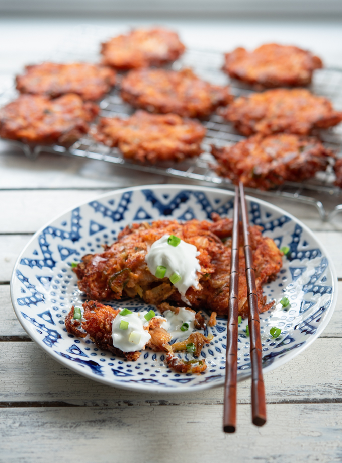 Cheesy Kimchi Potato Pancakes are served with sou cream on a plate.