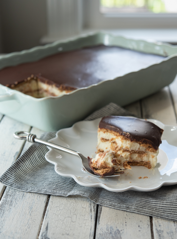 A slice of no bake eclair cake is served on a white plate with a fork.