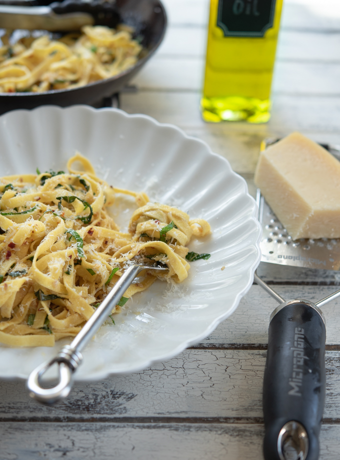 Pasta with Garlic, Anchovy, and Basil is topped with freshly grated parmesan cheese.