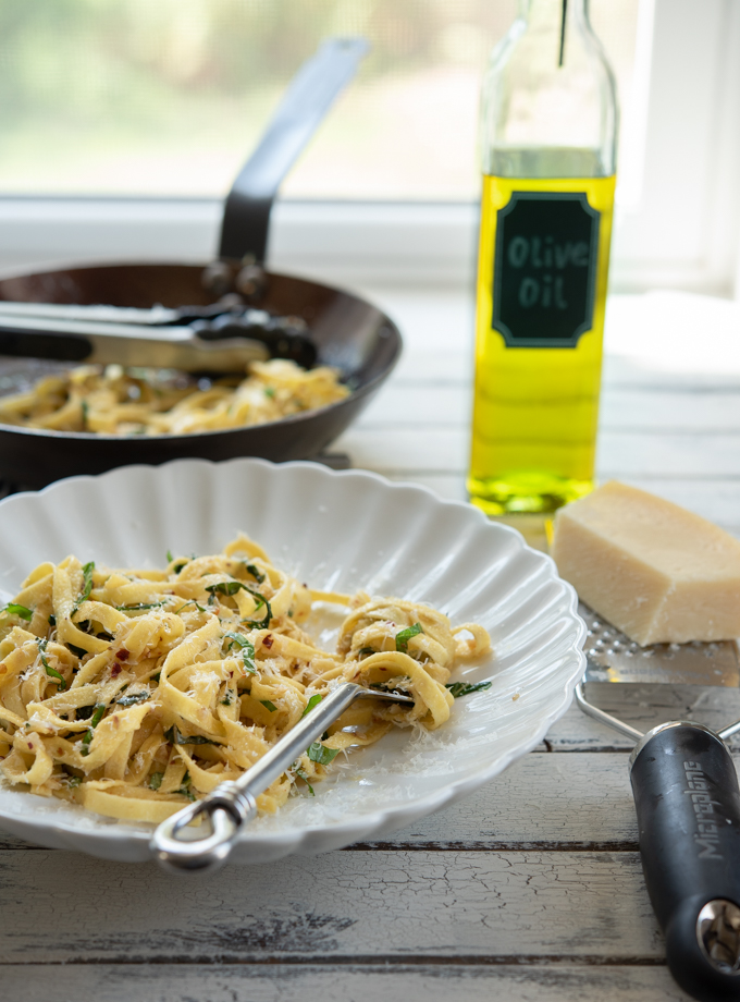Anchovy basil pasta in a bowl with grated cheese.
