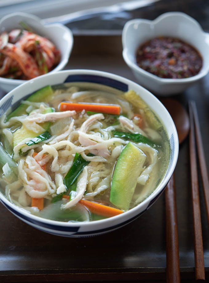 Korean knife cut noodle soup is cooked with chicken, zucchini and carrot in Korean herb broth.